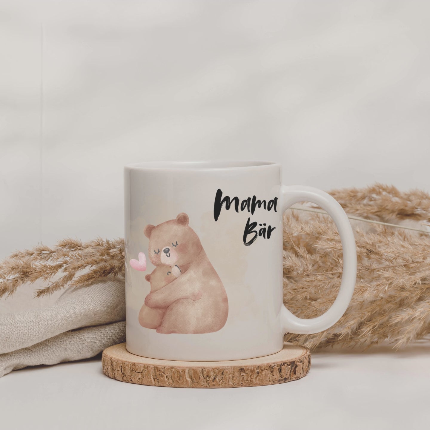 Weiße Tasse mit der Aufschrift "Mama Bär" und einem Motiv einer Mama-Bär die ihr Baby-Bär im Arm hält.