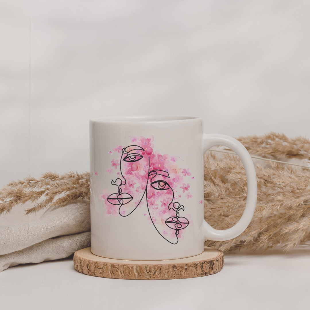 Weiße Tasse mit zwei Gesichtern die von pinker Farbe umgeben sind